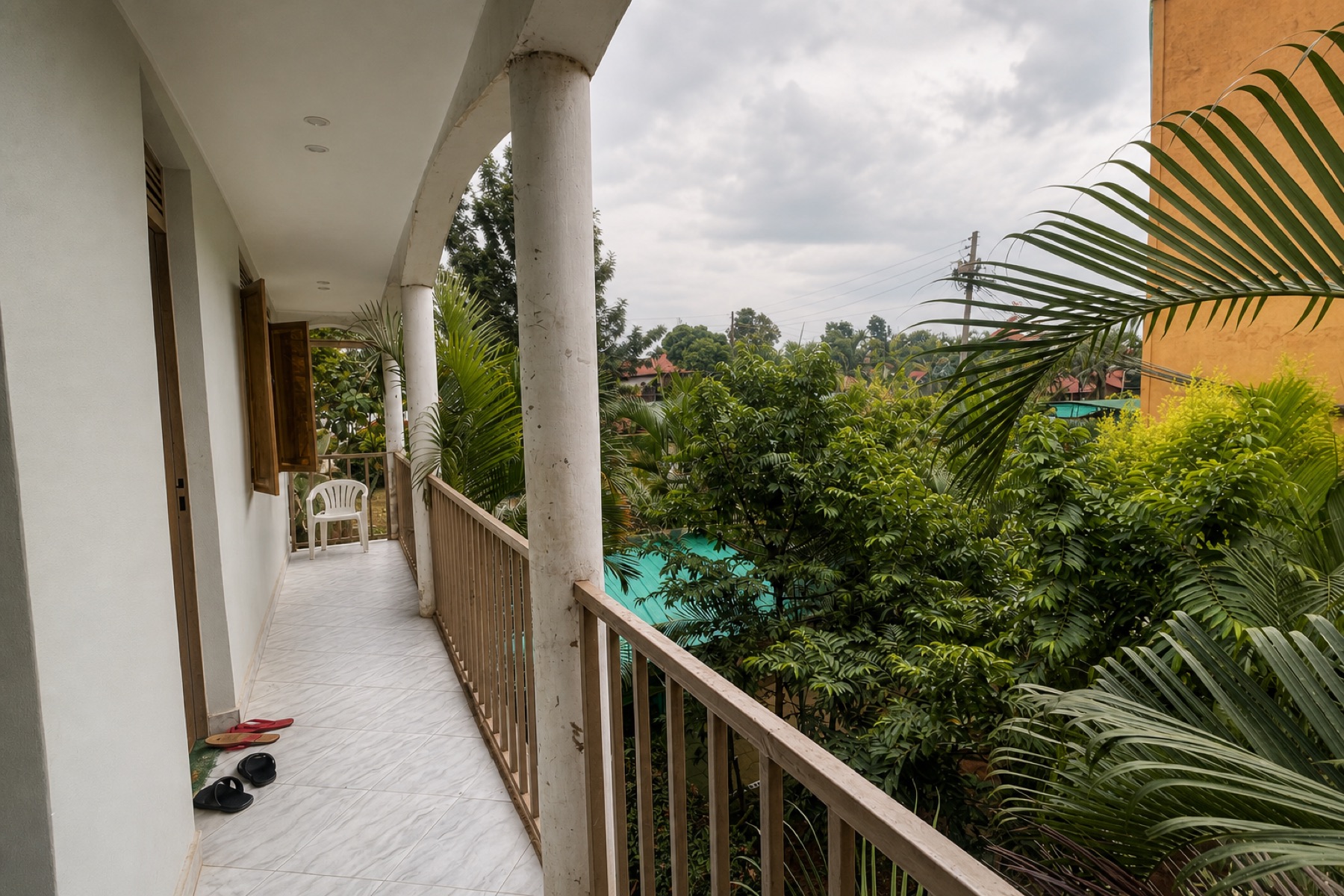 The balcony corridor outside the rooms at Maganjo, with palms beyond the rail